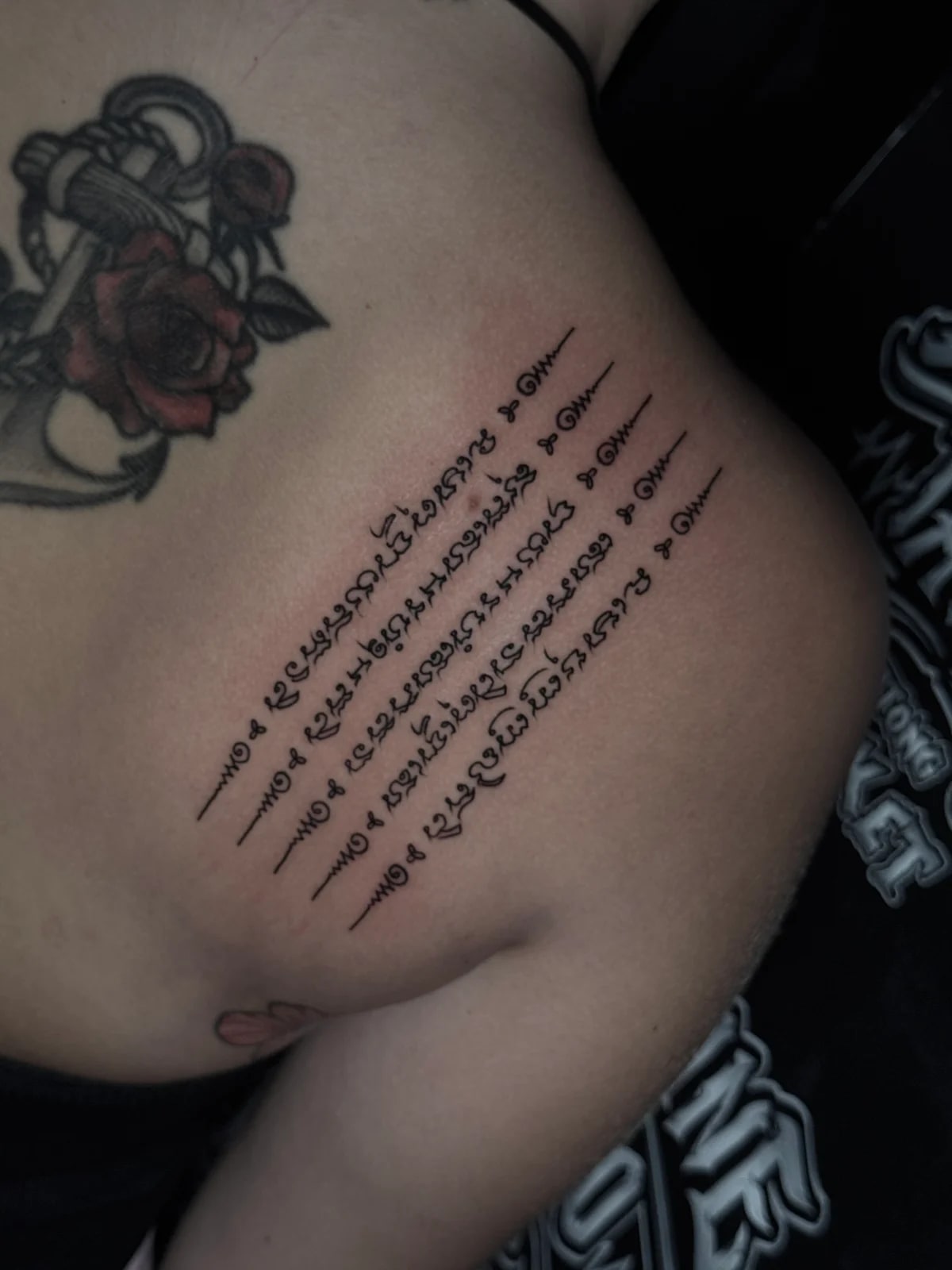 Hah Taew (Five Sacred Lines) Sak Yant with five vertical Khom script rows and unalome symbols on the ribcage at Bloodline Tattoo Phuket.