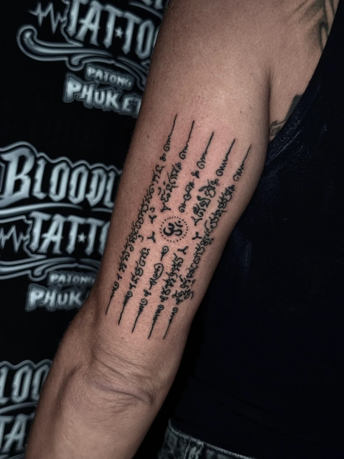 Hah Taew (Five Rows) Sak Yant with five Khom script columns and a central Om symbol on the inner forearm at Bloodline Tattoo Phuket.