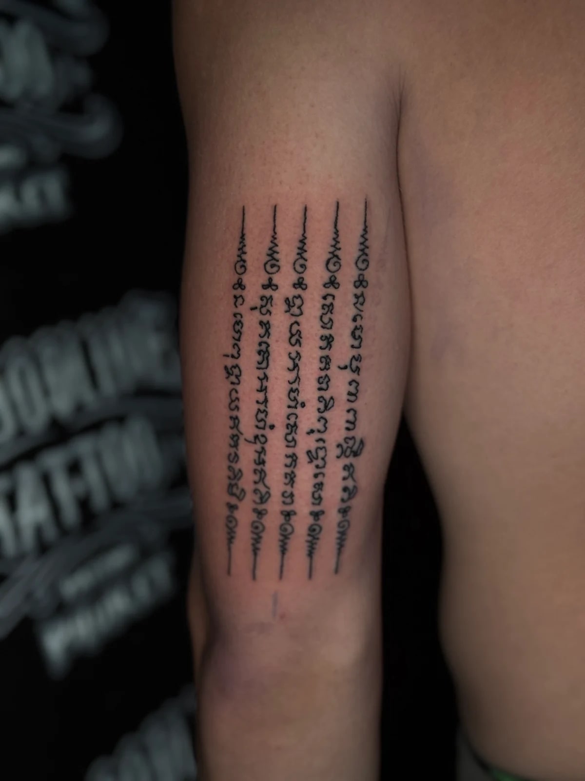 Hah Taew (Five Sacred Lines) Sak Yant with five vertical Khom script columns on the inner upper arm at Bloodline Tattoo Phuket.