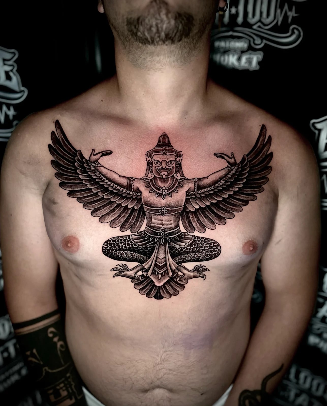 Garuda Sak Yant with outstretched wings, ornate headdress, and detailed feather shading centered on the chest at Bloodline Tattoo Phuket.