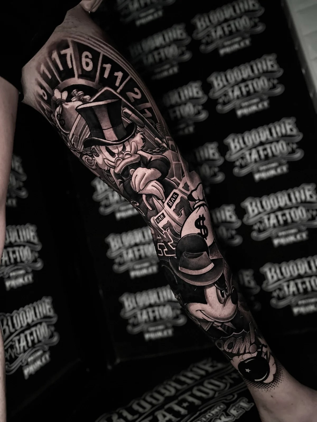 Chicano leg tattoo with Scrooge McDuck, fedora Mickey Mouse, a roulette wheel, slot reels, money bags, and a cartoon bomb at Bloodline Tattoo Phuket.