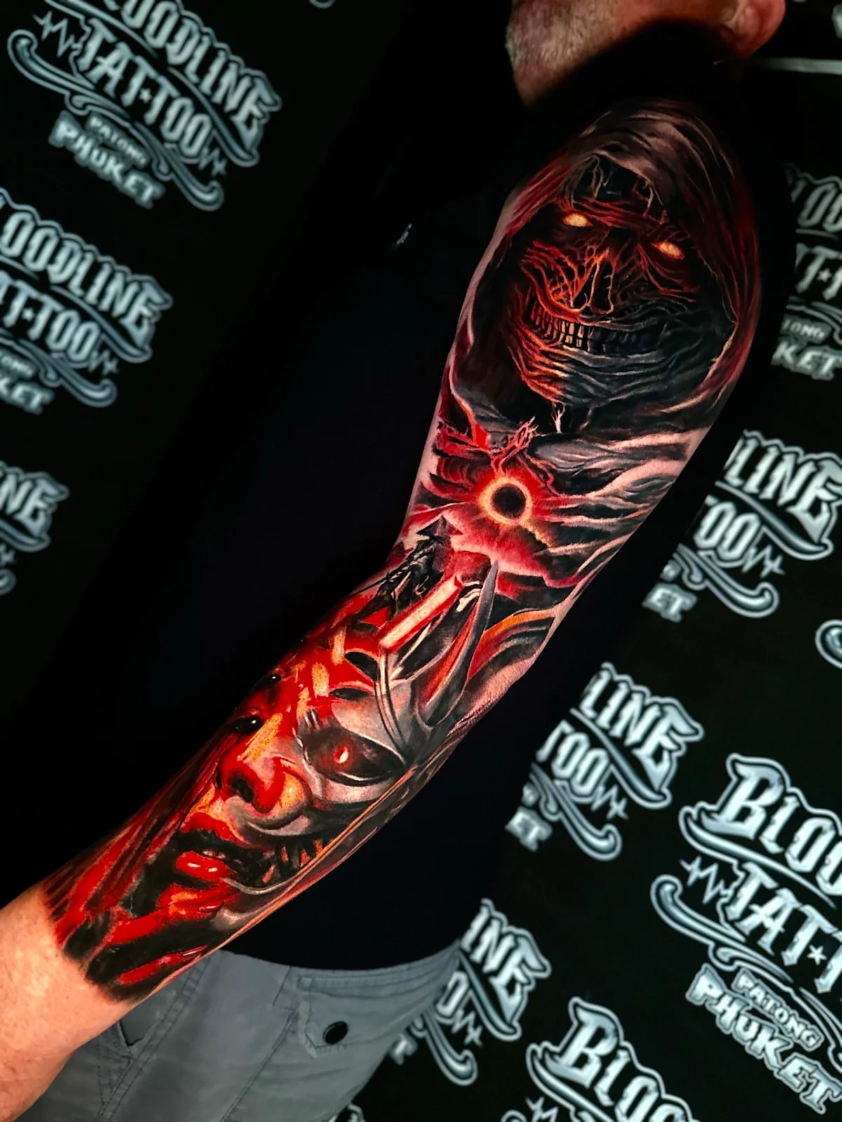 Dark fantasy colour sleeve with a hooded wraith, a glowing eclipse portal, and a layered Oni demon mask in red and orange at Bloodline Tattoo Phuket.