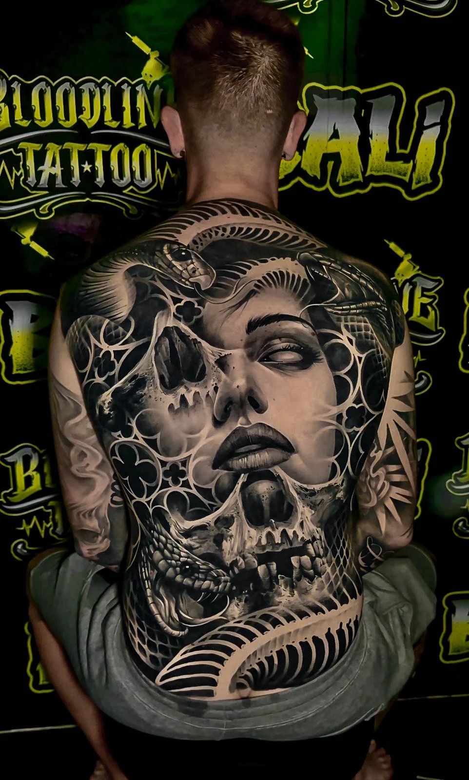 Healed full-back piece with a woman's face, skulls, and coiling snakes, showing smooth black-and-grey blending and strong healed contrast at Bloodline Tattoo Bali.