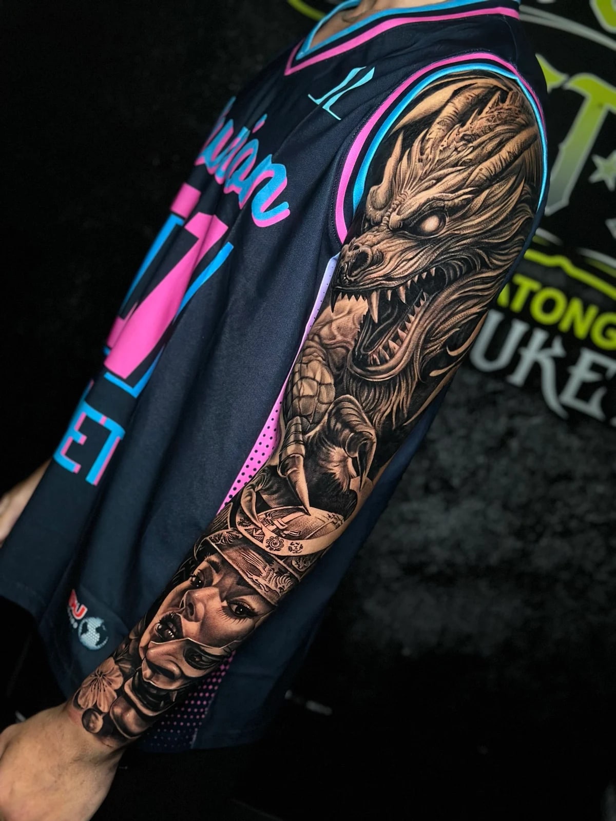 Japanese black and grey full sleeve with snarling dragon head on the upper arm, woman in kabuto on the forearm, and Hannya mask with cherry blossoms at Bloodline Tattoo Phuket.