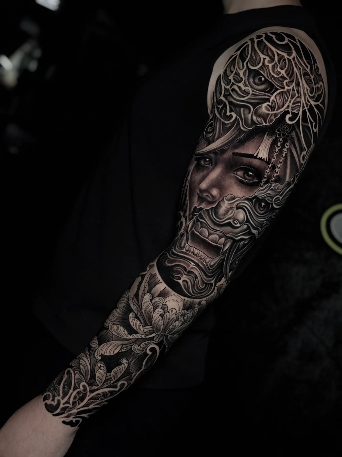 Japanese black and grey full sleeve blending a woman's portrait with Hannya mask, chrysanthemums, and wind-wave mikiri at Bloodline Tattoo Phuket.