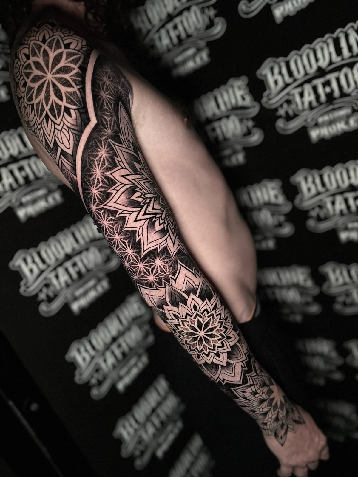 Black and grey mandala full sleeve with layered shoulder and forearm mandalas connected by Flower of Life dotwork grids at Bloodline Tattoo Phuket.