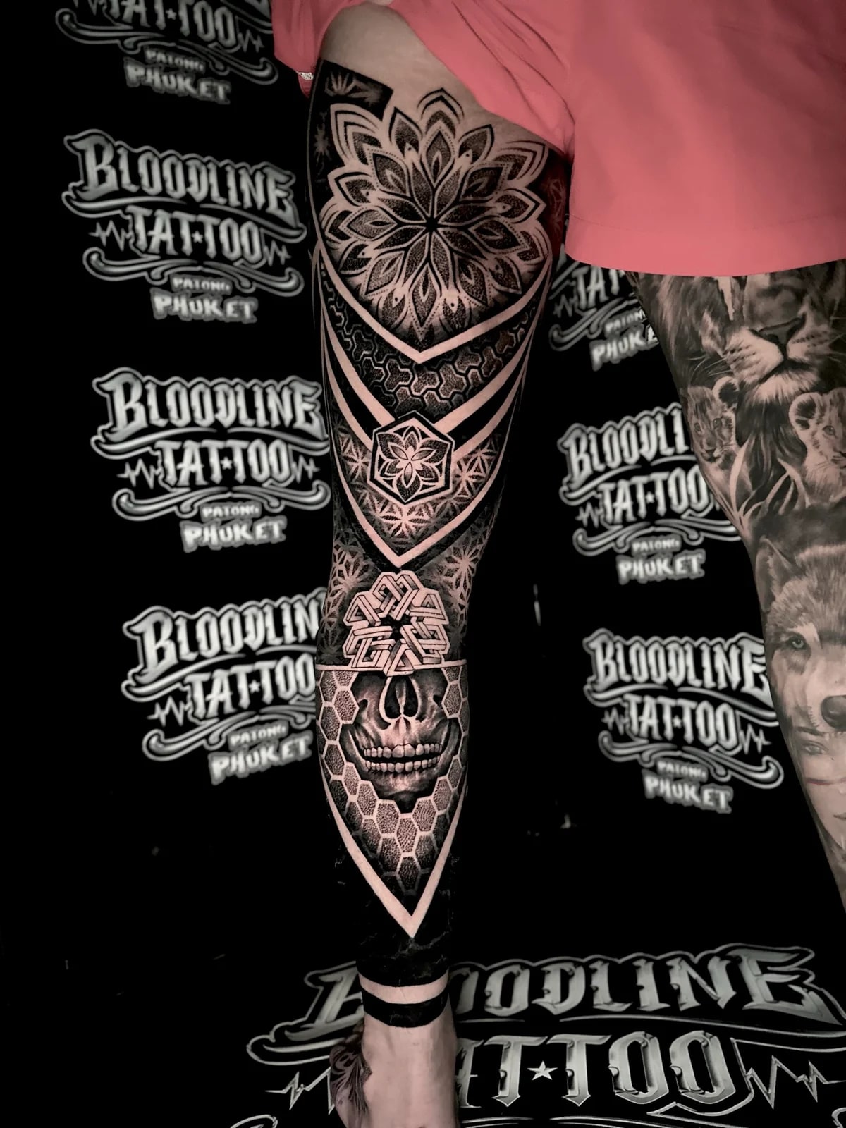 Front leg mandala tattoo with a thigh lotus mandala, a 3D geometric knee knot, and a skull set in a honeycomb shin grid at Bloodline Tattoo Phuket.