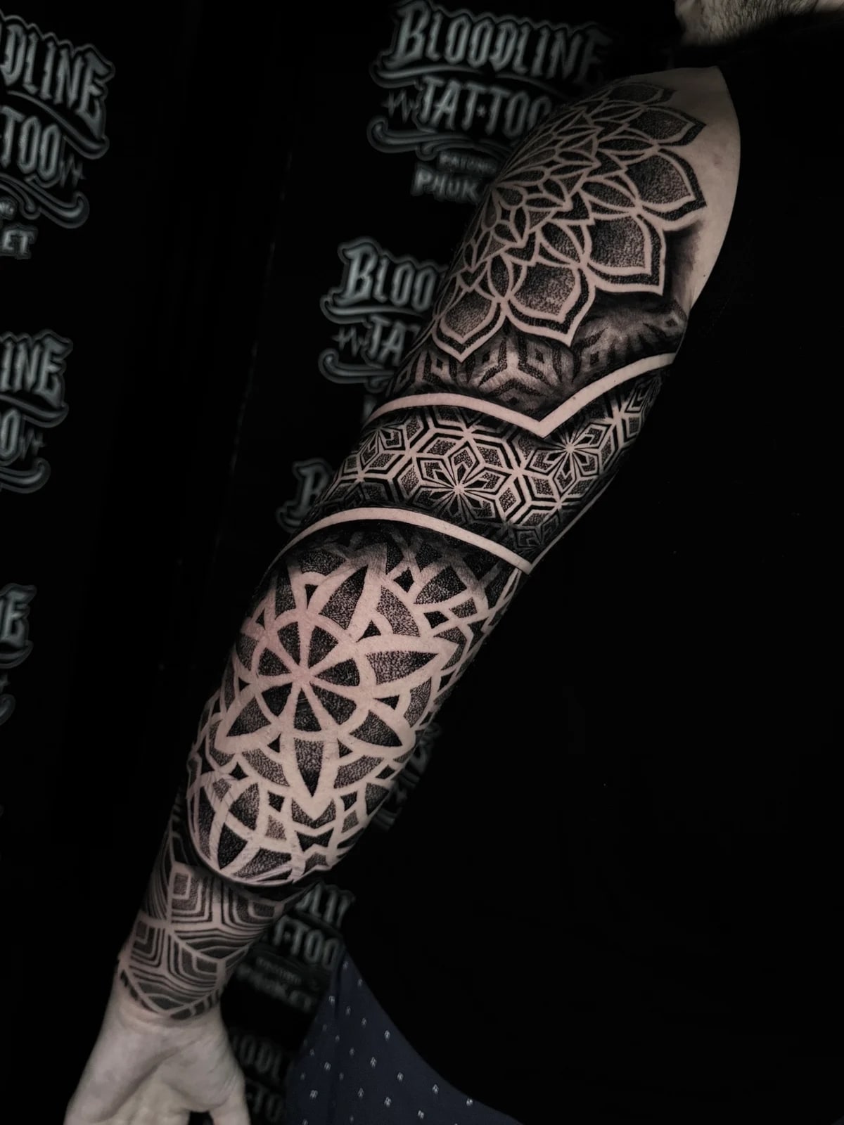 Black and grey mandala sleeve with dotwork shoulder and elbow mandalas separated by a hexagonal star band at Bloodline Tattoo Phuket.