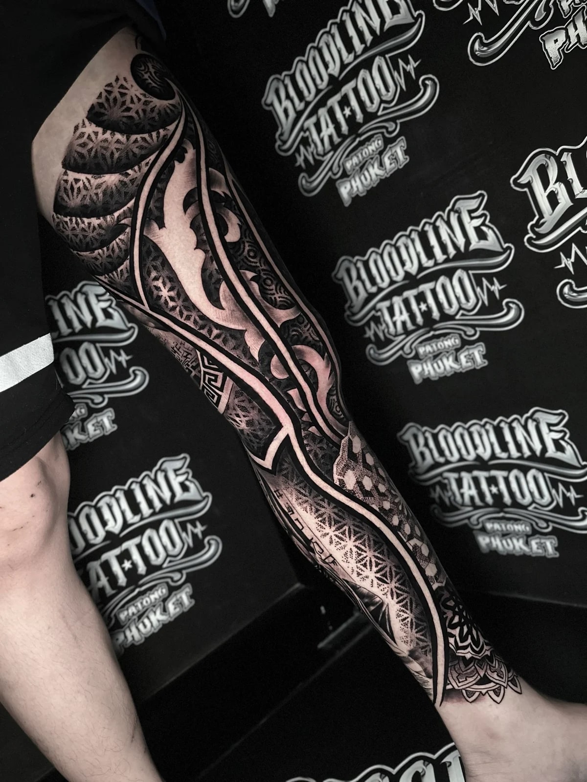Full leg geometric mandala sleeve with Flower of Life panels, honeycomb grids, and bold ornamental blackwork separators at Bloodline Tattoo Phuket.