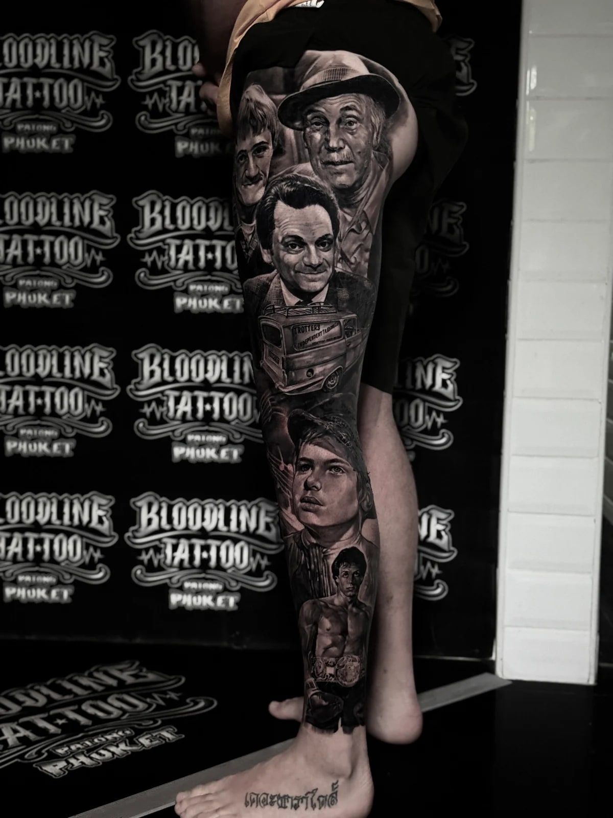Detailed black and grey realism full leg sleeve tattoo featuring Only Fools and Horses characters, the Trotters Reliant van, and Rocky Balboa at Bloodline Tattoo Phuket.