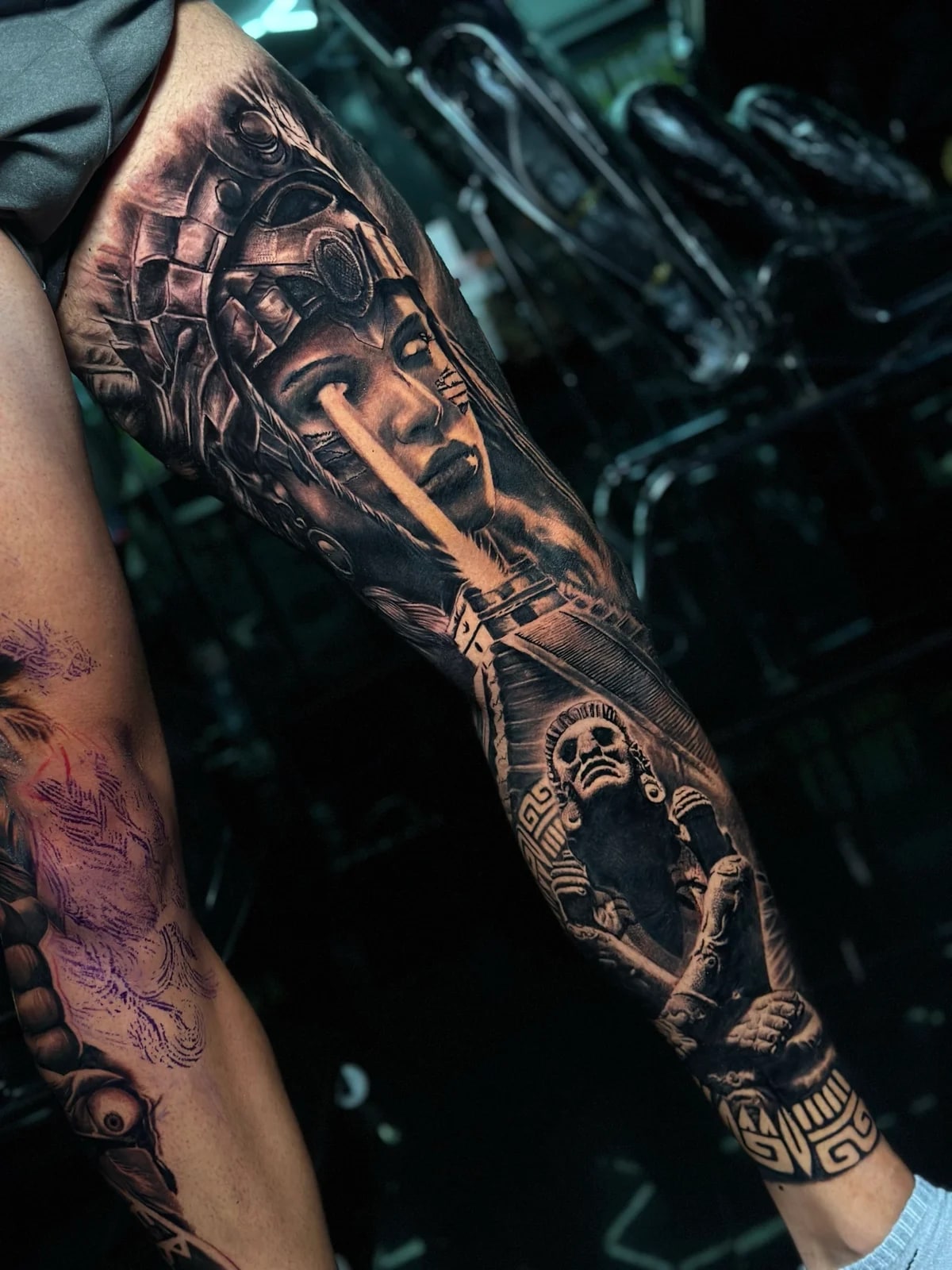 Detailed black and grey realism full leg sleeve tattoo featuring a Mayan woman with ornate crown and light beam, ancient statue idol, and stepped pyramid at Bloodline Tattoo Phuket.