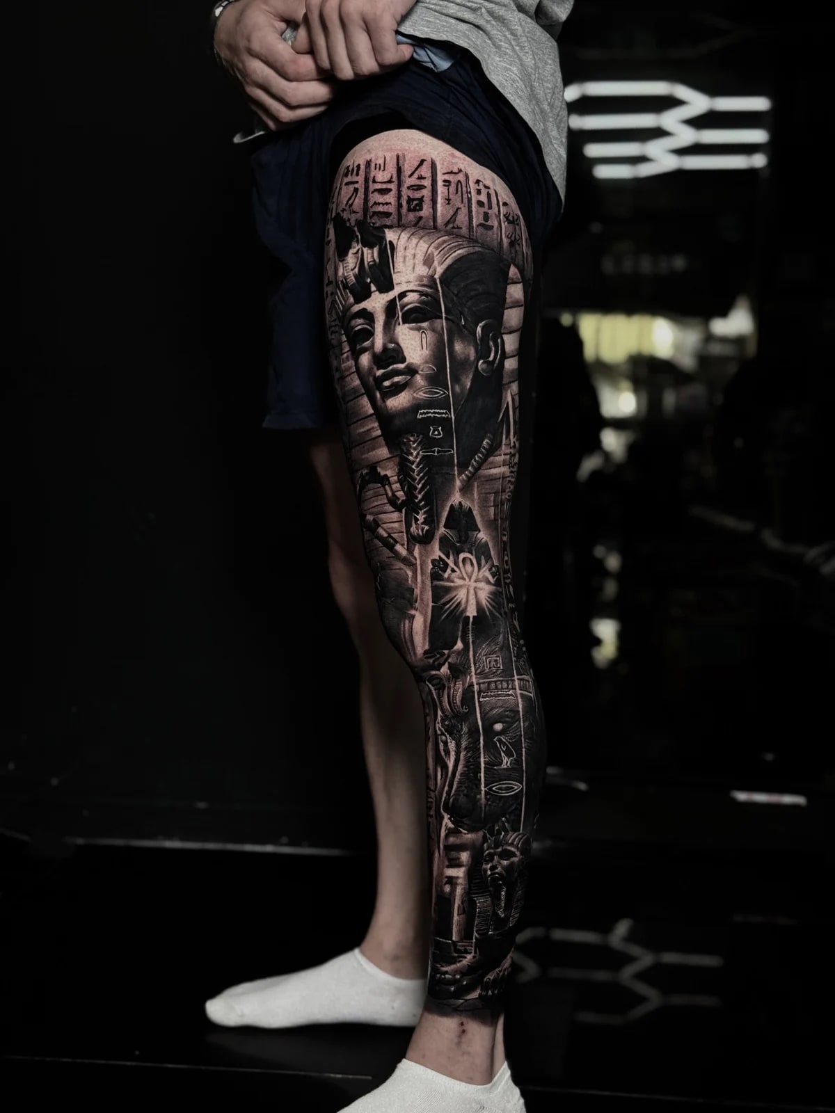 Detailed black and grey realism full leg sleeve tattoo featuring an Egyptian Pharaoh portrait, hieroglyphics, glowing Ankh, and sphinx at Bloodline Tattoo Phuket.