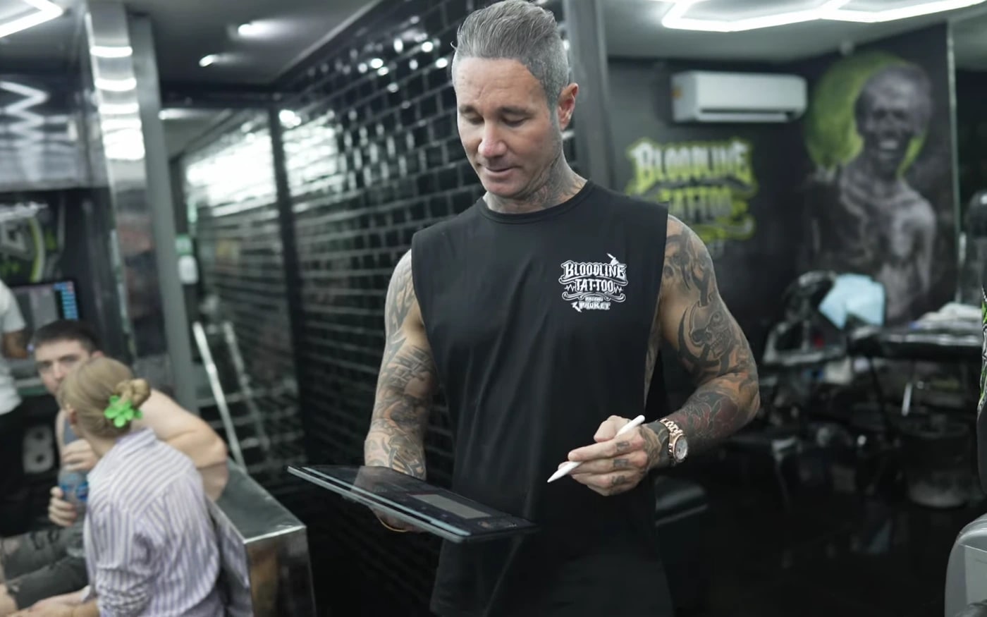 Artist reviewing a digital design on a tablet inside Bloodline Tattoo Phuket