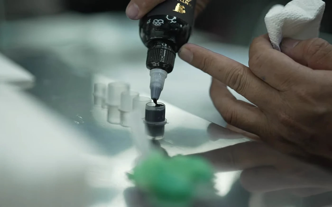 Tattoo artist pouring sterile ink into single-use caps at Bloodline Tattoo Phuket