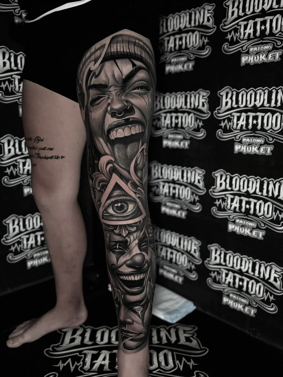 Chicano payasa portrait leg sleeve with all-seeing eye and clown masks at Bloodline Tattoo Phuket.