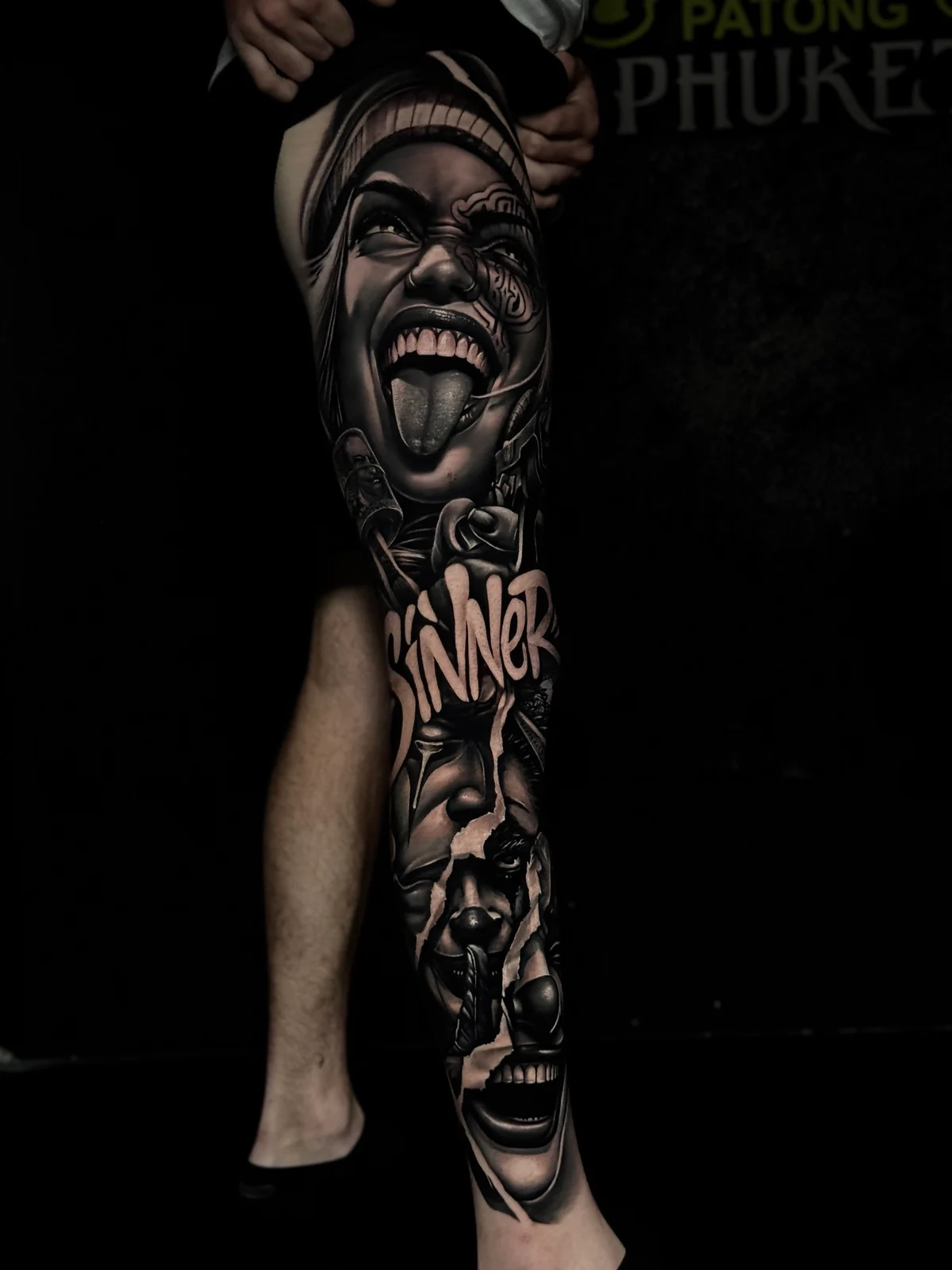 Chicano Sinner script leg sleeve with payasa portrait and torn layered faces at Bloodline Tattoo Phuket.
