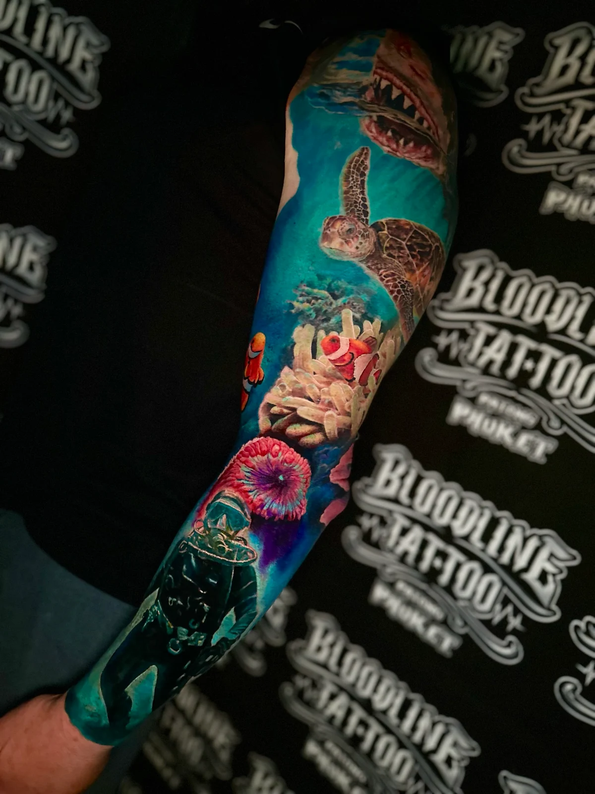 Underwater colour sleeve with a shark, sea turtle, clownfish in anemone, and a scuba diver in deep blue water at Bloodline Tattoo Phuket.